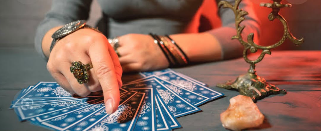 Mână indicând cărți de tarot în lumină caldă de lumânare